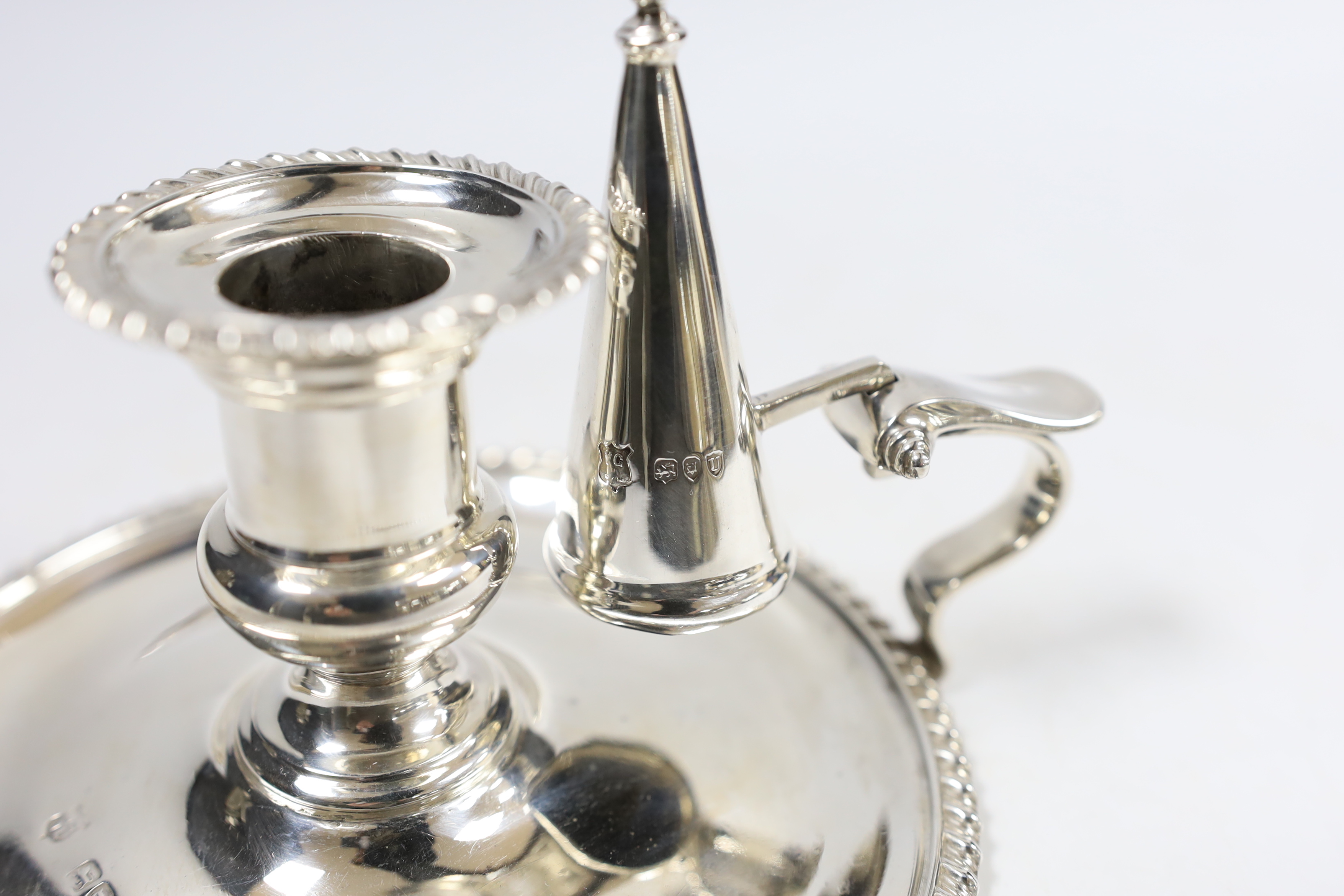 A late Victorian silver chamberstick and matching extinguisher, by Goldsmiths & Silversmiths, London, 1895, with gadrooned border, base diameter 15cm, 9.7oz.